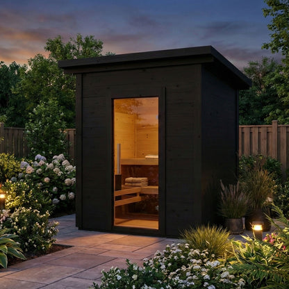 SaunaLife Model G2B black outdoor sauna lit up in a garden at dusk